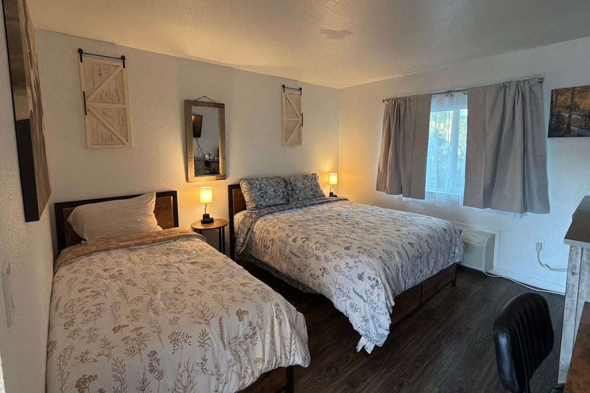 Een slaapkamer met twee bedden, een spiegel en een raam met gordijnen.