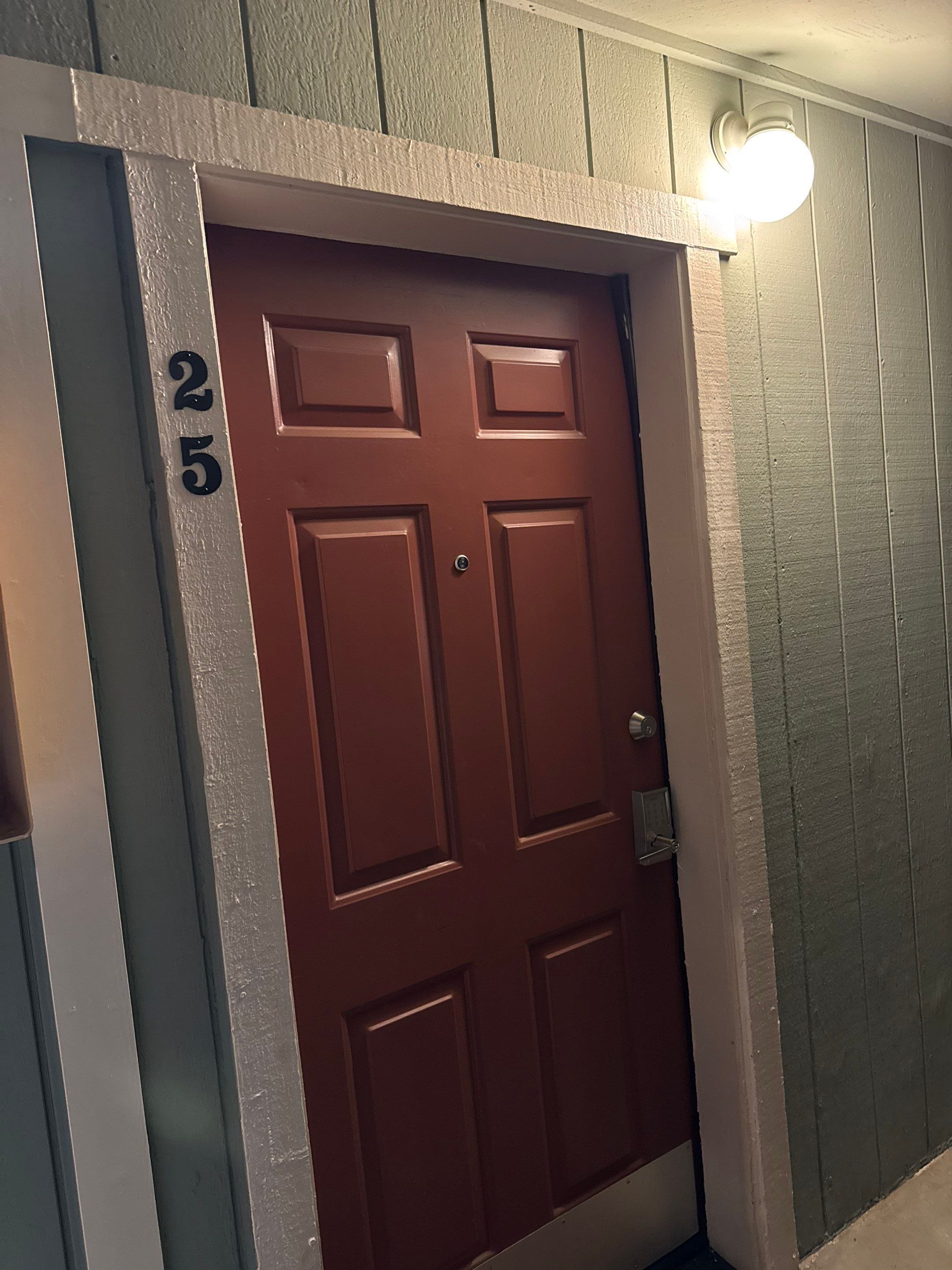 A brown door with a number "25" on the wall beside it.