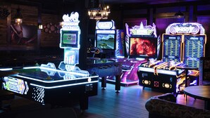 A variety of arcade games with neon lights and a disco ball in a dimly lit room. - Pemberton Hotel (Pemberton)