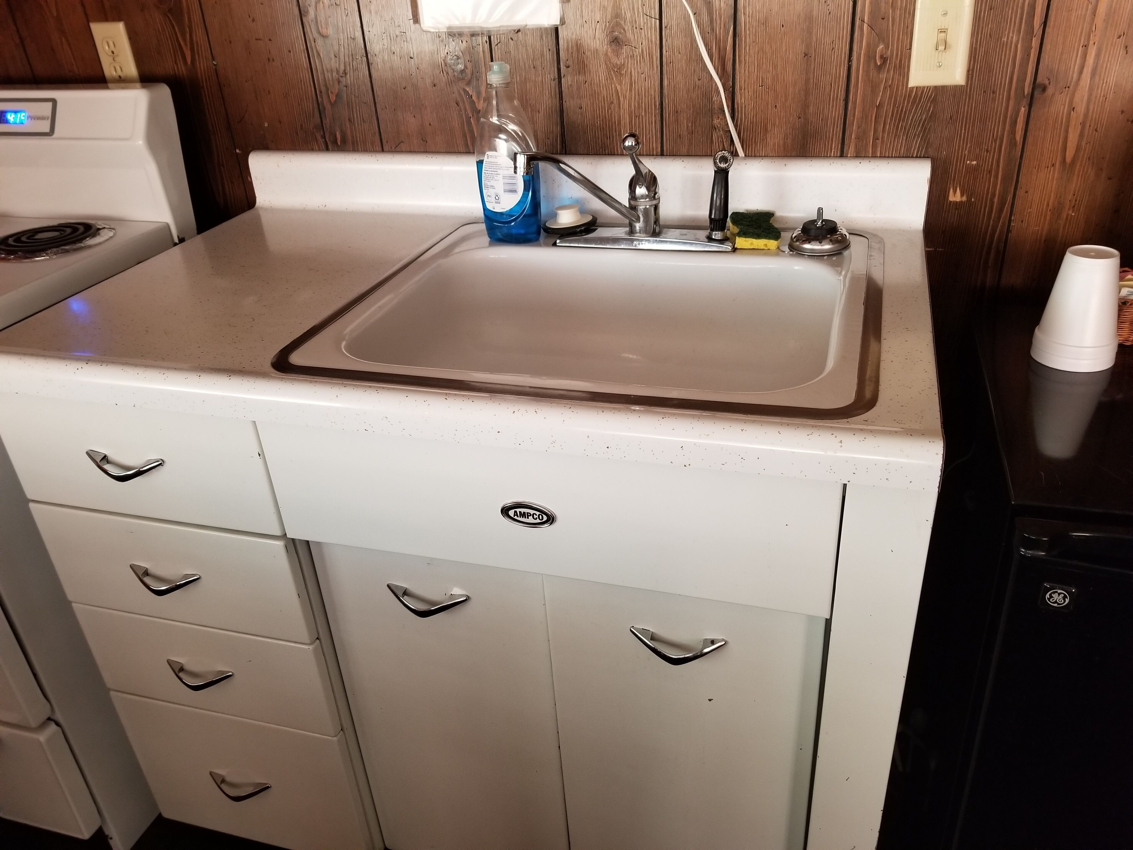 A kitchen with a white countertop, a sink, and a stove.