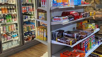 Una tienda de comestibles con bebidas frías, aperitivos y productos envasados en estantes.