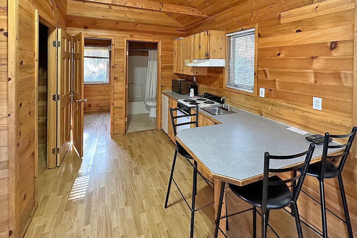 A compact kitchen with wooden walls and a central island, a sink, and a stove.