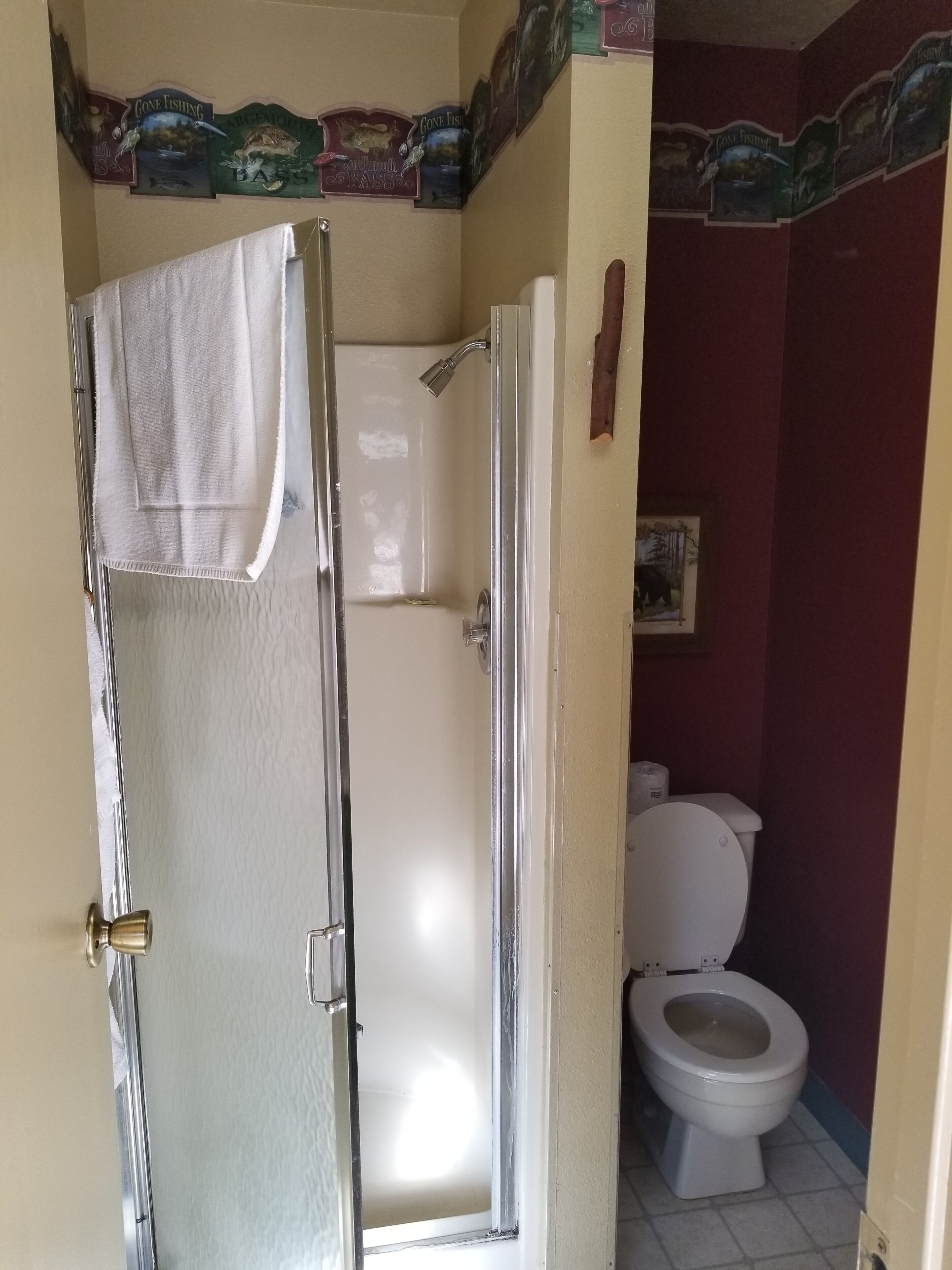 Ein Badezimmer mit Dusche, Toilette und einer Tür, an der ein Handtuch hängt.