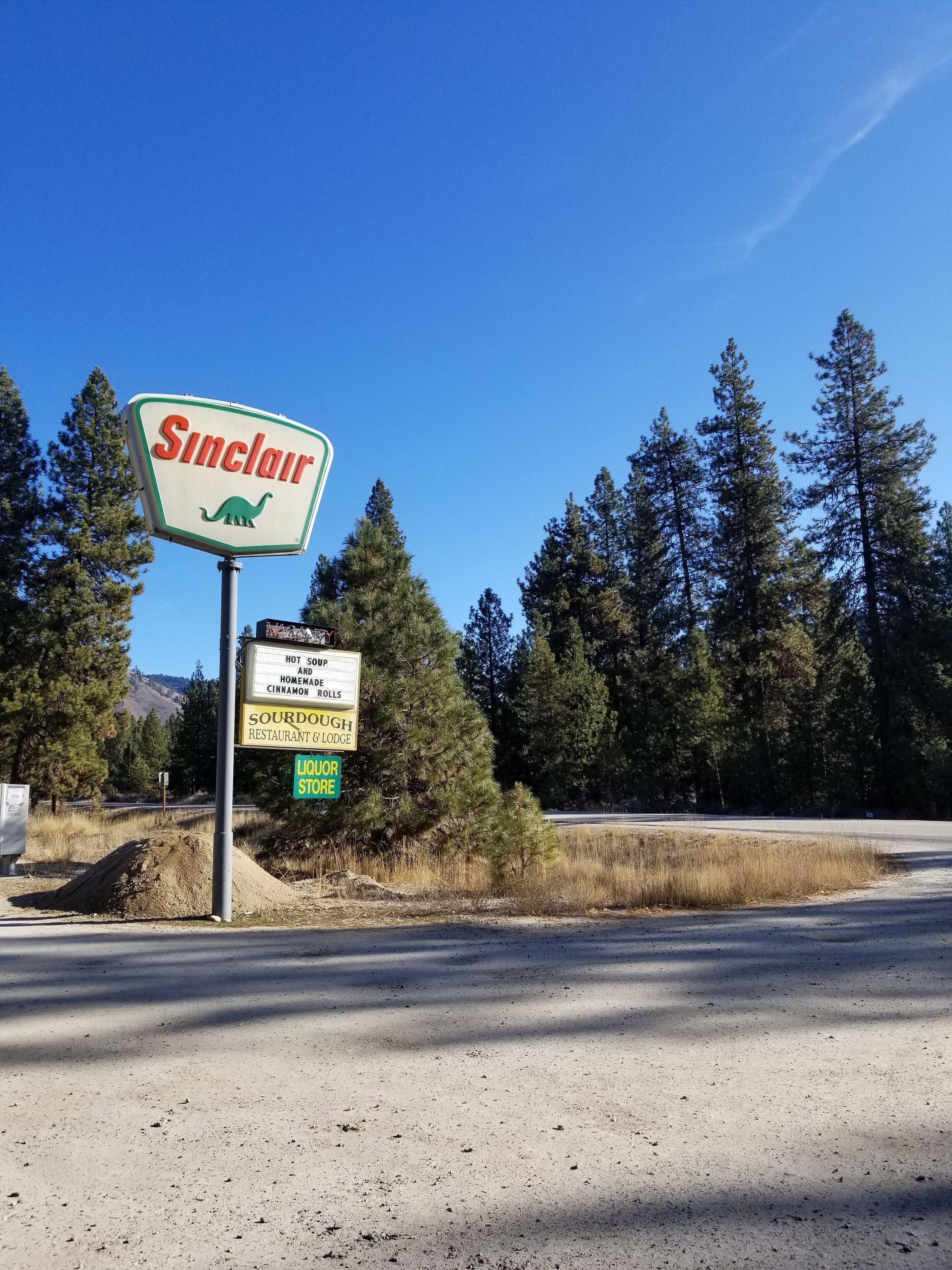 A sign for Sinclair with a dinosaur logo, indicating a restaurant and lodge.