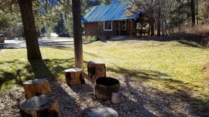 A rustic cabin with a blue roof, surrounded by a natural landscape with trees and a gravel path. - Sourdough Lodge (Lowman)