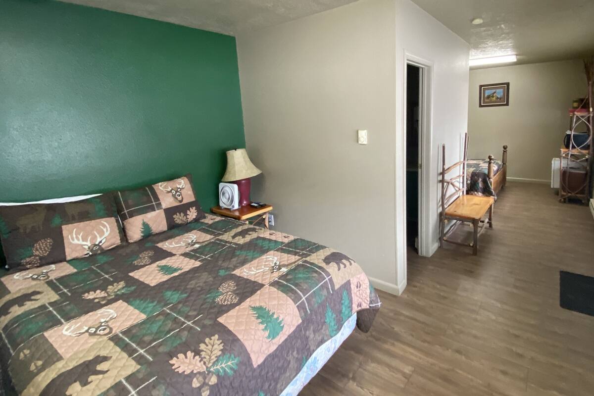A bedroom with a bed, a nightstand, a lamp, a chair, and a television.