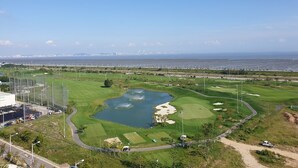 A golf course with a pond, surrounded by green fields and a clear sky. - Goodday Airtel (Incheon)