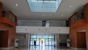 A spacious lobby with a high ceiling and skylight, featuring a central entrance with glass doors and a ramp leading to an upper level. - Goodday Airtel (Incheon)