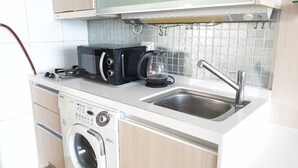 A compact kitchen with a washing machine, a microwave, and a sink. - Goodday Airtel (Incheon)