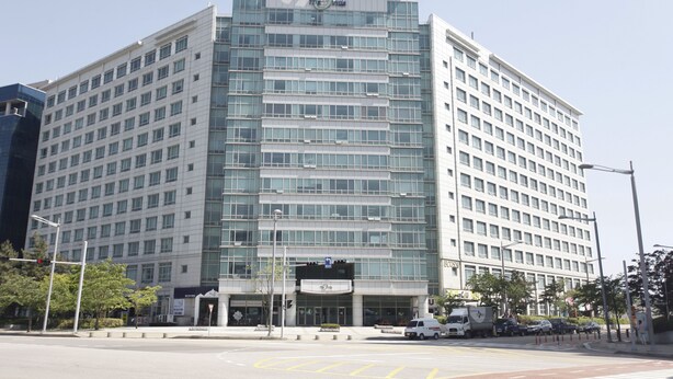 A multi-story hotel with a modern glass facade, a prominent entrance, and a parking area visible in front. - Goodday Airtel (Incheon)