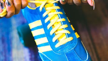 Una persona atando cordones amarillos a una zapatilla azul.