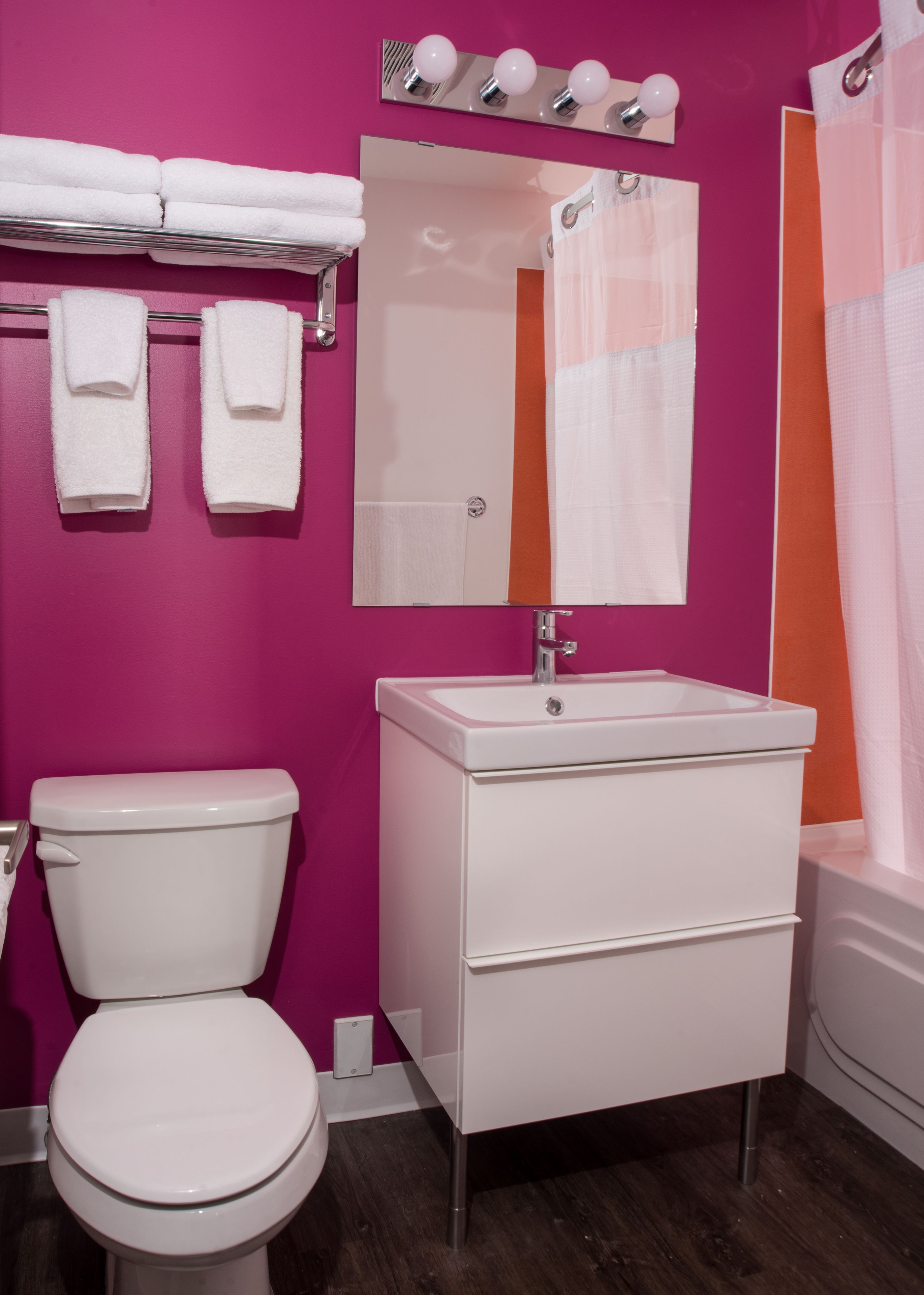 Un baño con inodoro blanco, lavabo blanco con espejo y cortina de ducha.