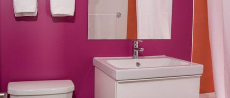 A bathroom with a white toilet, a white sink with a mirror above it, and a shower curtain.
