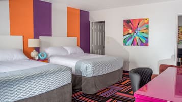 Una habitación de hotel con dos camas, un cuadro abstracto de colores y una alfombra con un diseño vibrante.