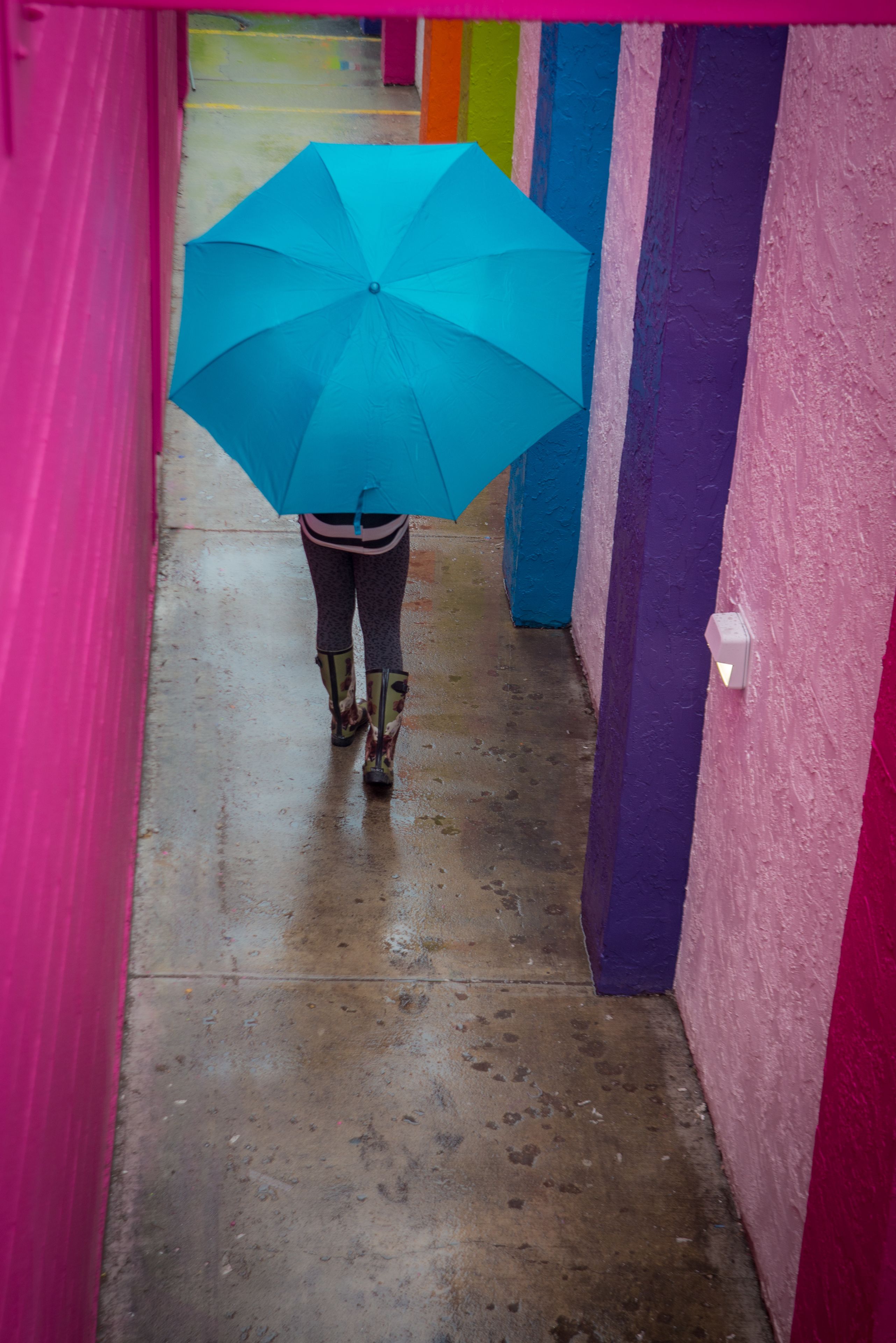 A person walking down a corridor with colorful walls and a wet floor.