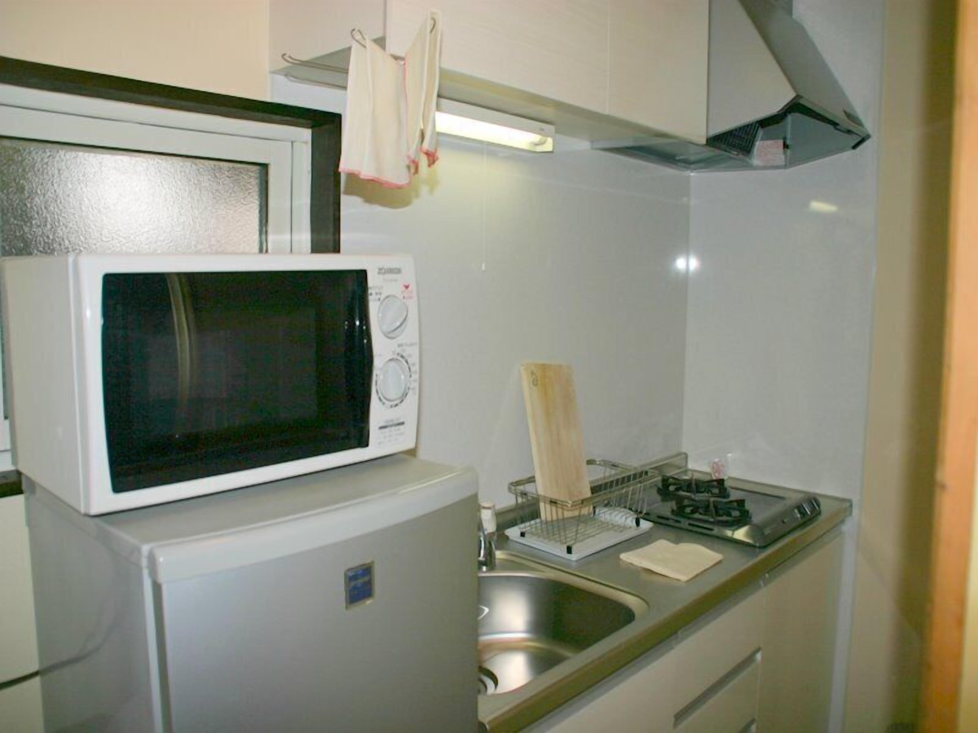 Une cuisine compacte équipée d’un four à micro-ondes, d’un petit réfrigérateur, d’un évier et d’une cuisinière.