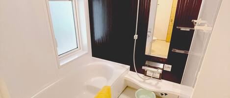 A modern bathroom with a bathtub, a small toilet, and a shower.
