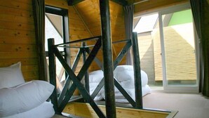 A wooden cabin room with a bed, a window, and a wooden ceiling structure. - Winkel Village (Otaru)