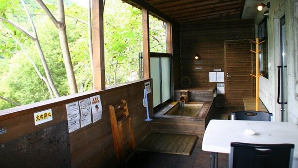 A wooden cabin with a wooden deck, a hot tub, and a table with chairs. - Winkel Village (Otaru)