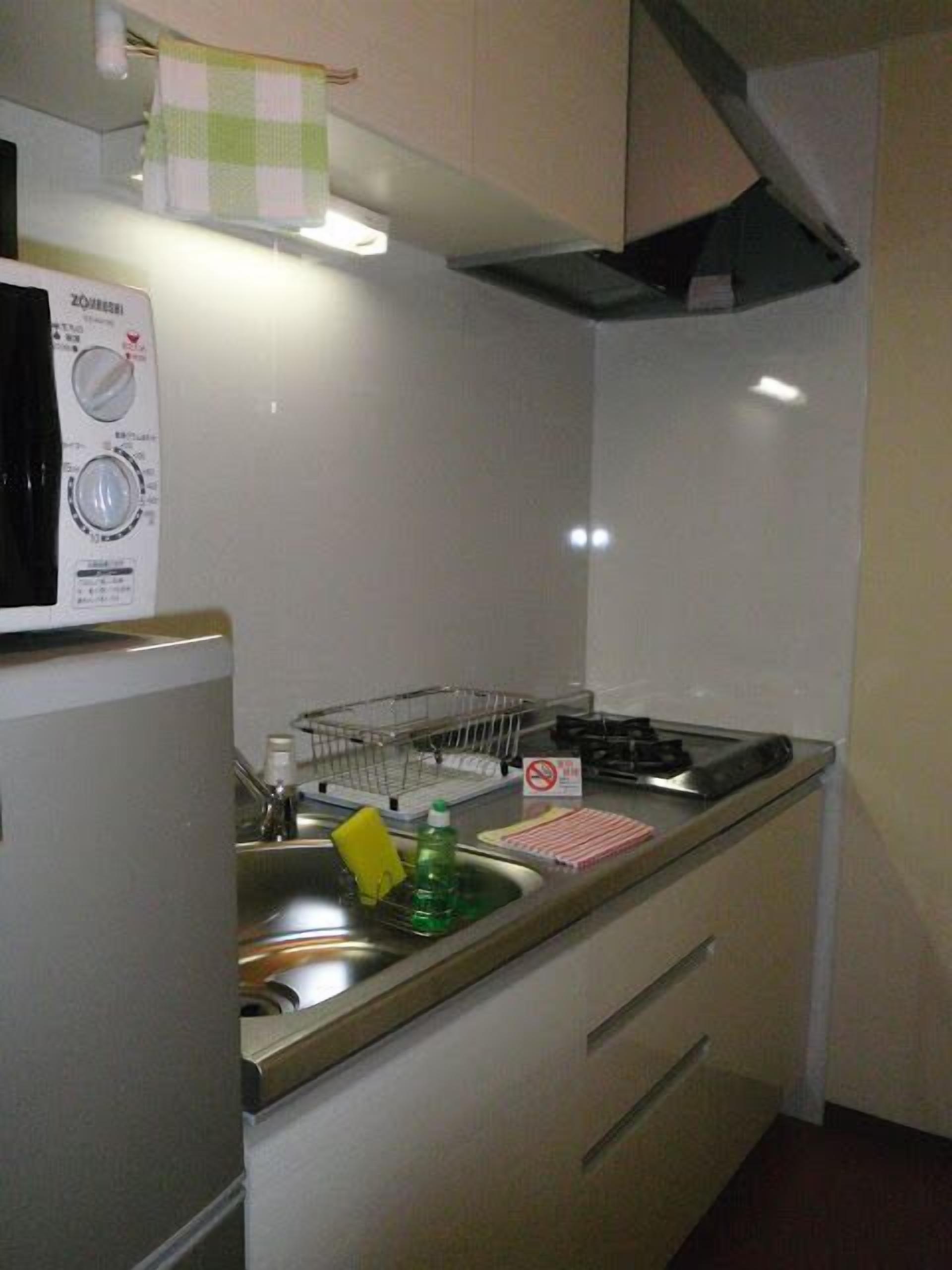 A compact kitchen with a microwave, sink, and a small dish rack.