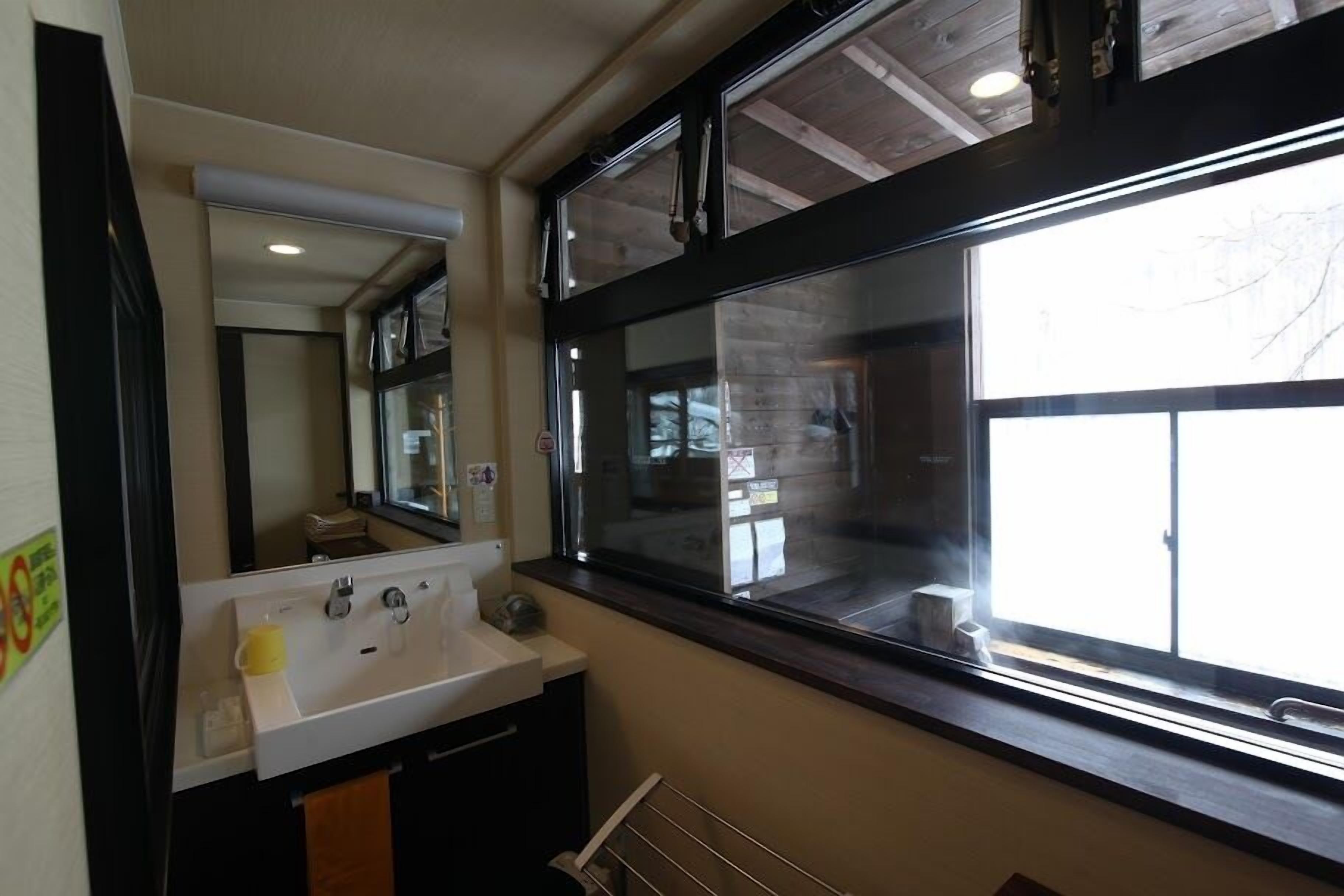 A bathroom with a large window, a sink, and a mirror.