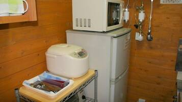 A compact kitchen with a microwave, a small refrigerator, and a food warmer on a wooden countertop.