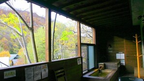 A wooden cabin with large windows, a wooden interior, and a view of trees. - Winkel Village (Otaru)