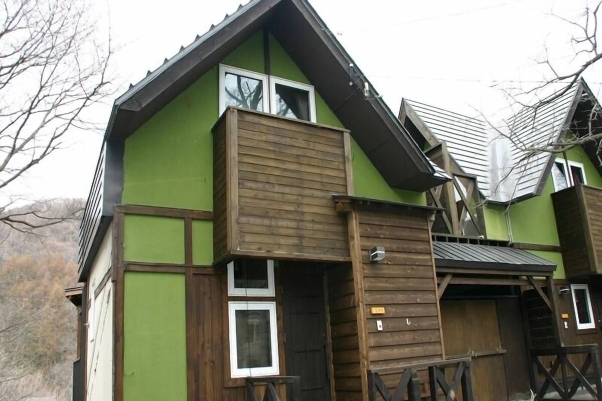 A two-story building with a green facade and wooden accents.