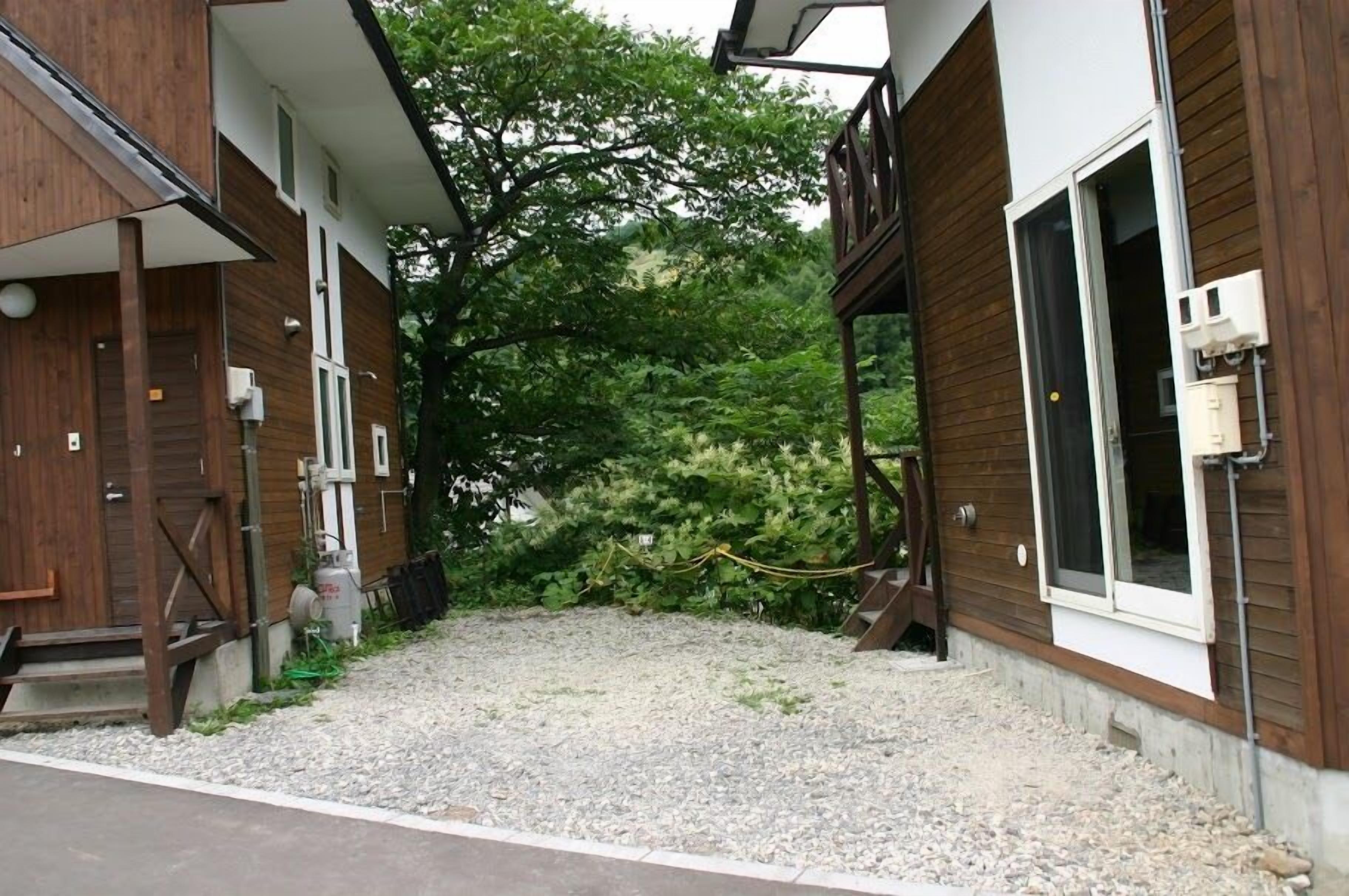 A modern building with a gravel driveway, wooden exterior, and a rope barrier.