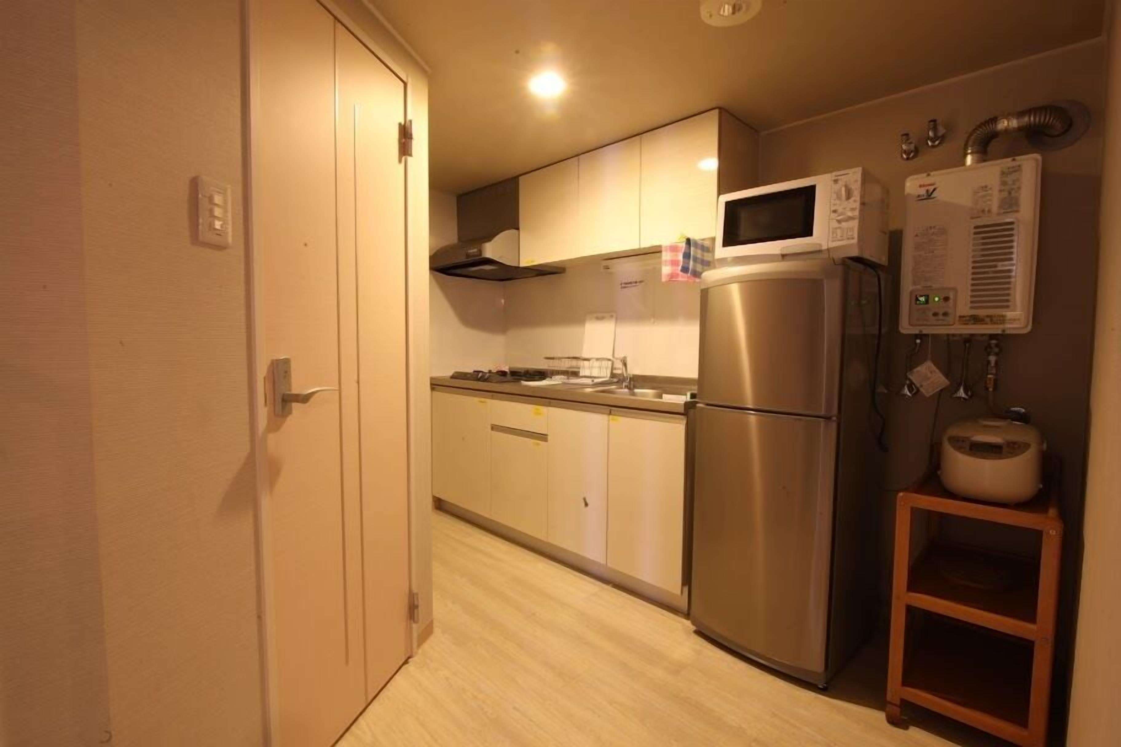 A compact kitchen with a stainless steel refrigerator, microwave, and a water heater.