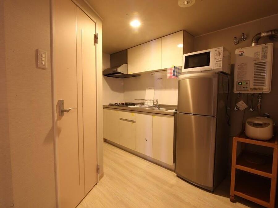 A compact kitchen with a stainless steel refrigerator, microwave, and a water heater.