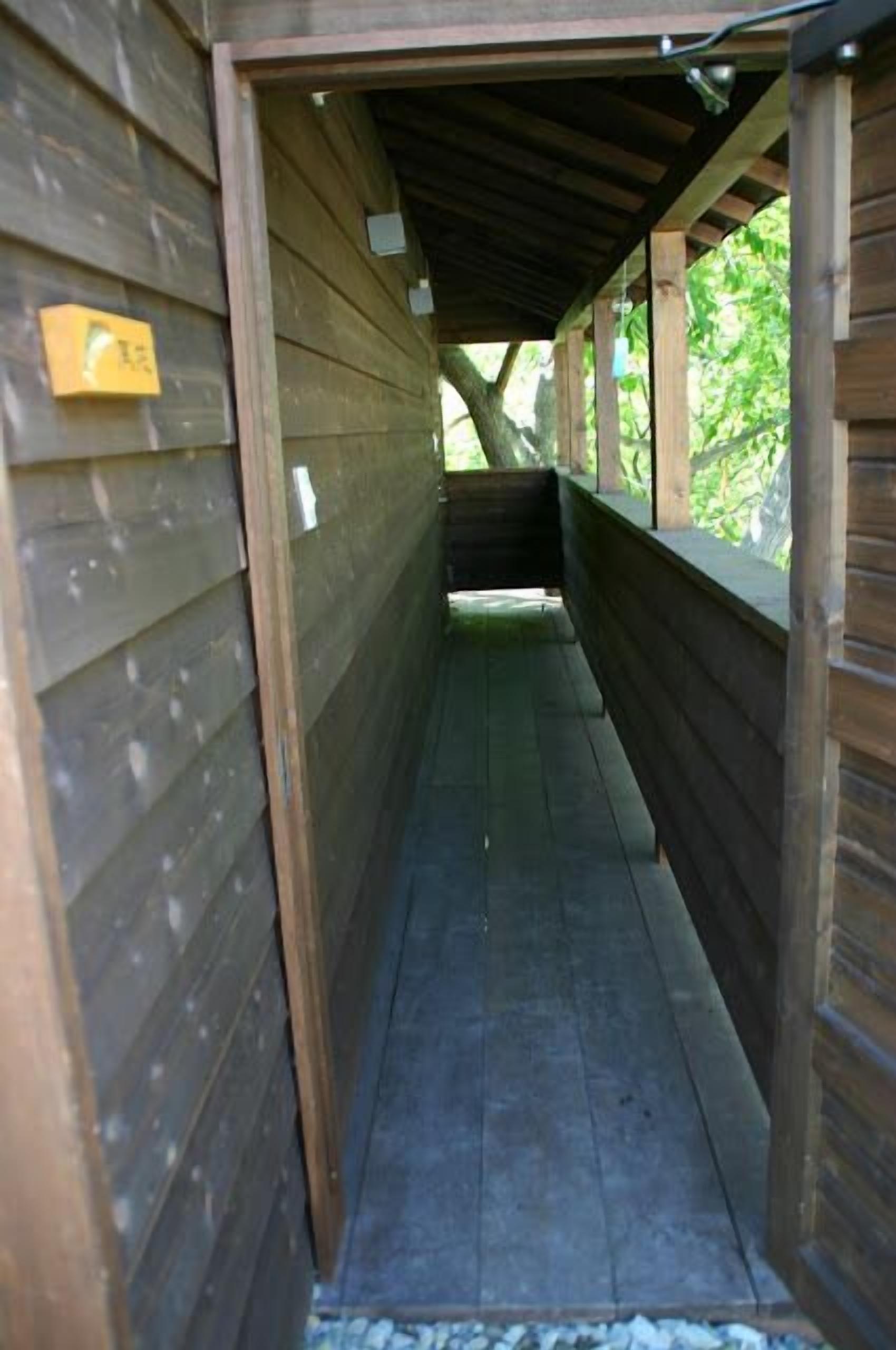 A covered wooden corridor with benches, wooden walls, and a small window.