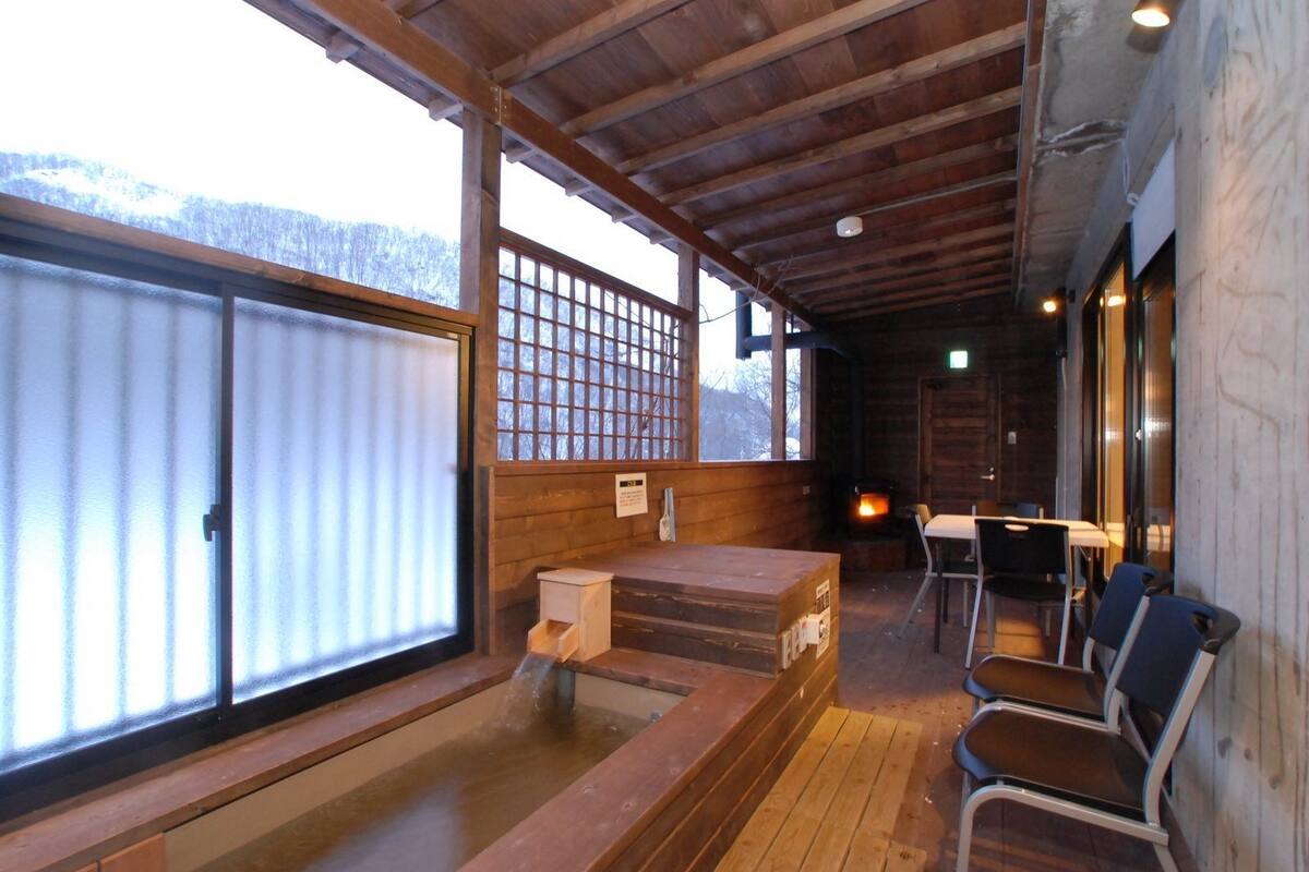 A wooden interior with a fireplace, seating area, and large windows.