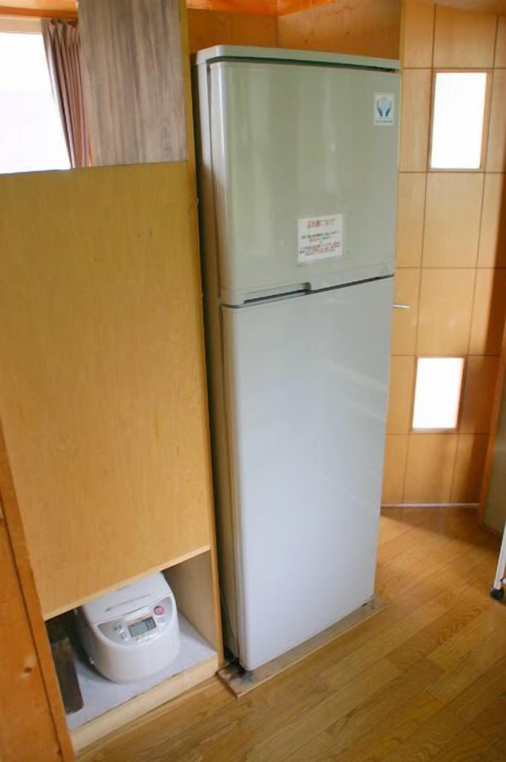 A compact kitchen with a white refrigerator, a small countertop, and a wooden cabinet.