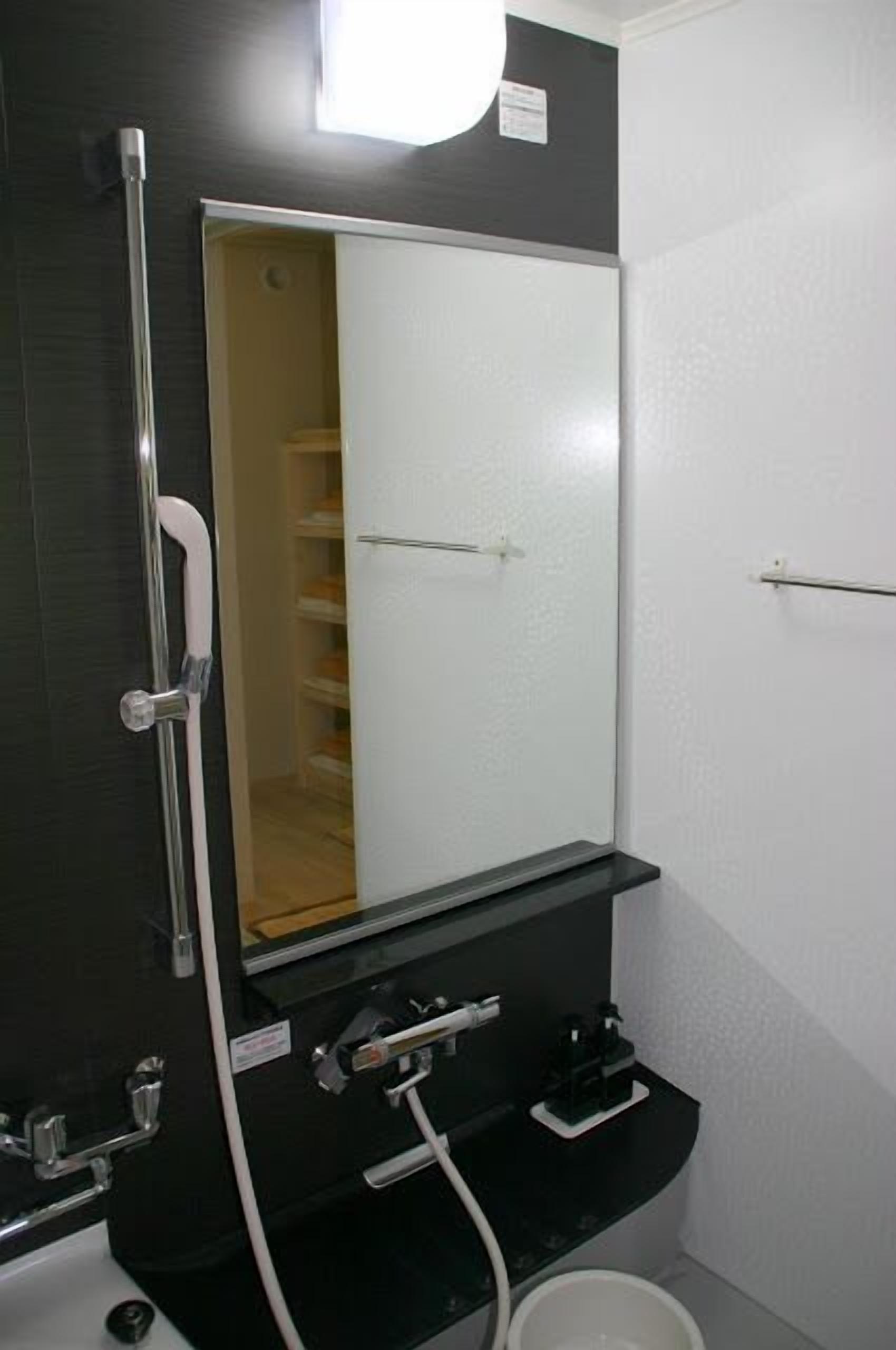 Et badeværelse med spejl, bruser og toilet.