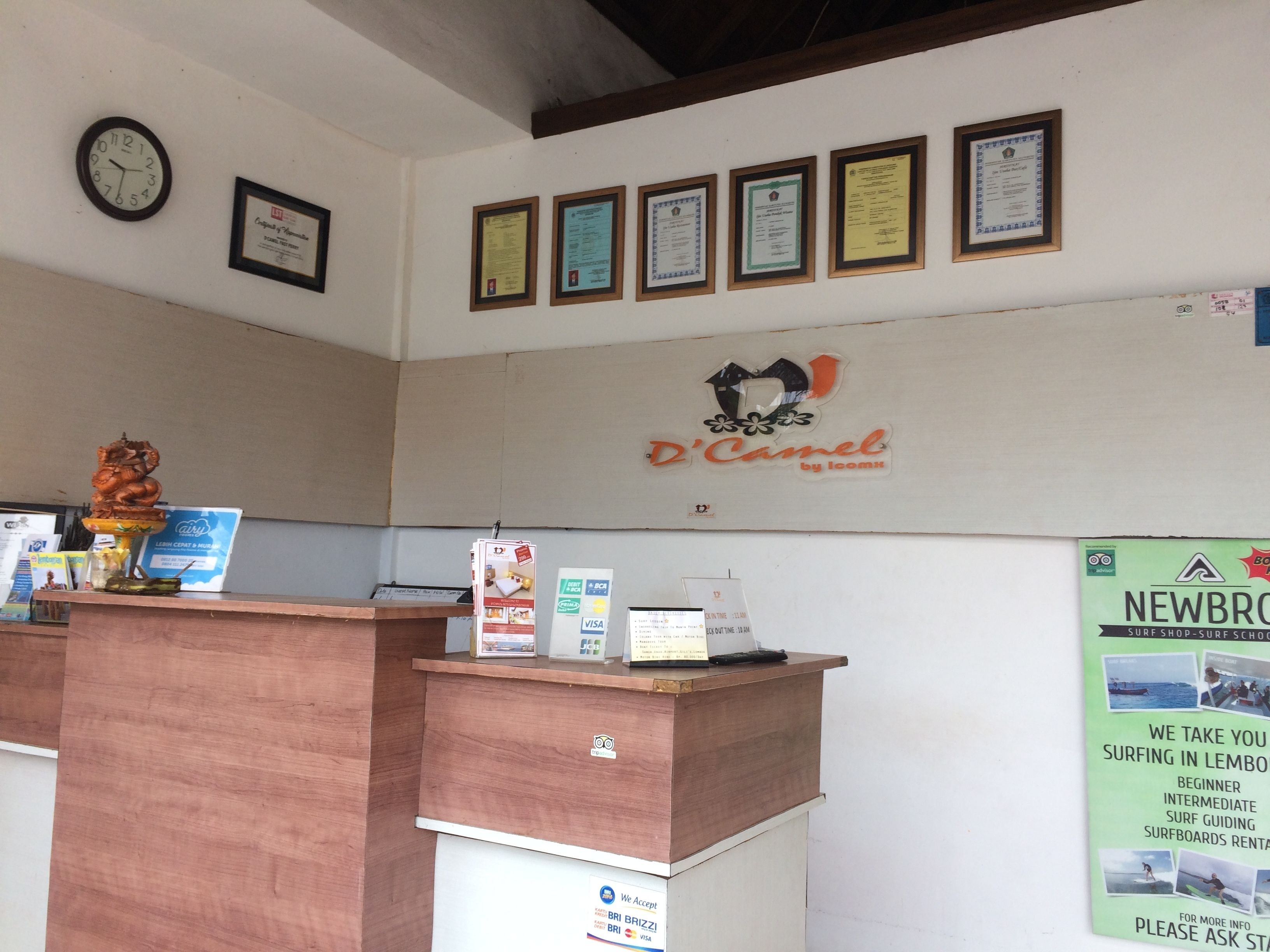 A reception desk with framed certificates, a clock, and a logo for 'D'Camel by Icomix'.