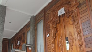 Een houten deur met ingewikkelde houtsnijwerken, een houten bankje en een kleine tafel.