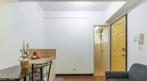 Un espacio habitable compacto con kitchenette, comedor y zona de ducha.