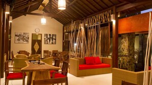 Une pièce spacieuse avec un plafond en bois, un canapé agrémenté de coussins rouges et un coin repas avec des meubles en bois.
