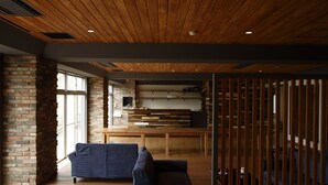 A modern interior with a wooden ceiling, a brick wall, and a seating area with a sofa. - Kyou Bar Lounge & Inn (Sendai)