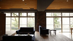 A spacious room with large windows, a wooden ceiling, and a stone pillar. - Kyou Bar Lounge & Inn (Sendai)