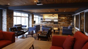 A modern lounge area with wooden flooring, red sofas, and a bar area in the background. - Kyou Bar Lounge & Inn (Sendai)