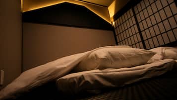 A dimly lit hotel room with a bed, a wall-mounted air conditioner, and a window with a grid pattern.