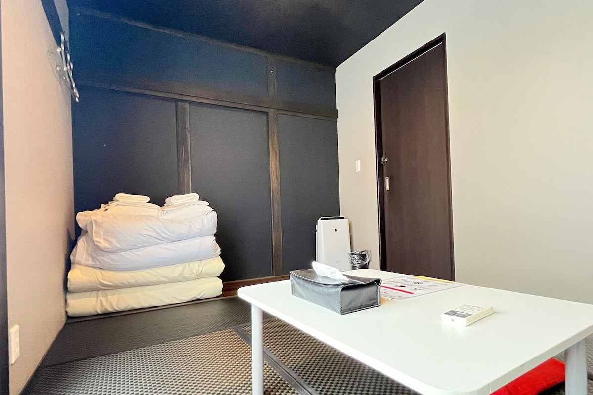 Um quarto de hotel pequeno, com uma cama, uma escrivaninha e uma porta.