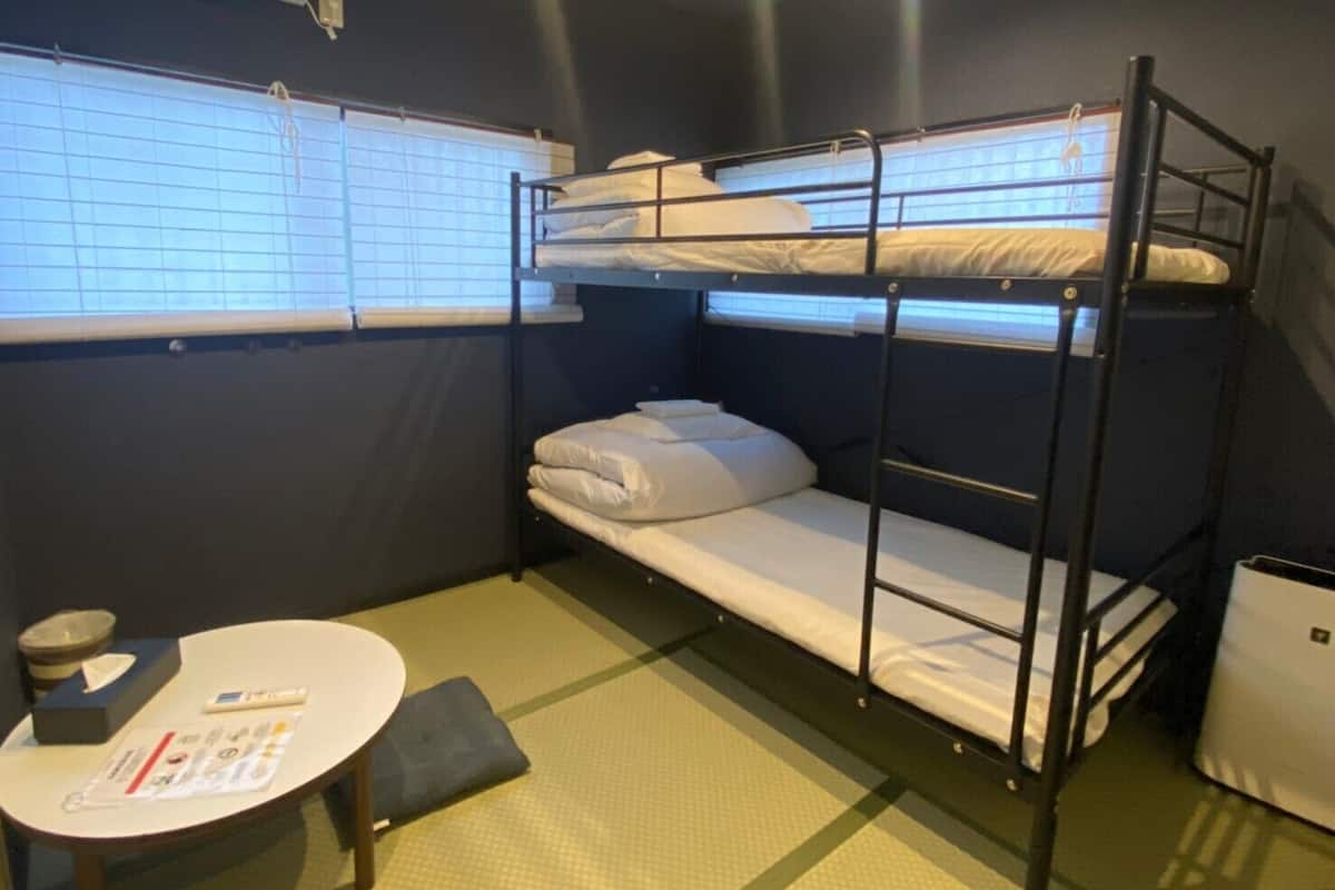 Quarto com beliche, uma pequena mesa e janela.