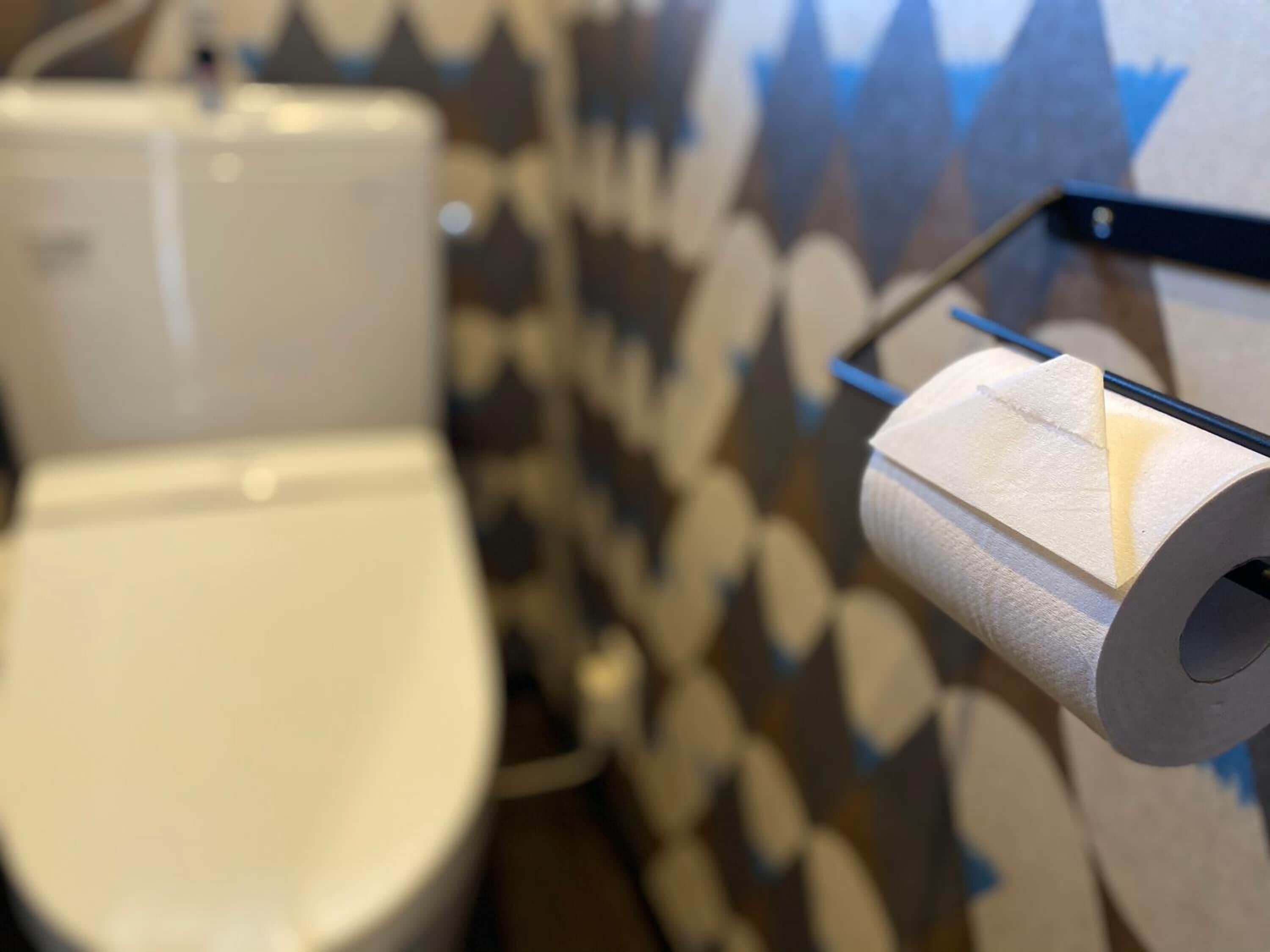 Un rollo de papel higiénico sujeto a la pared en un baño con papel pintado estampado.