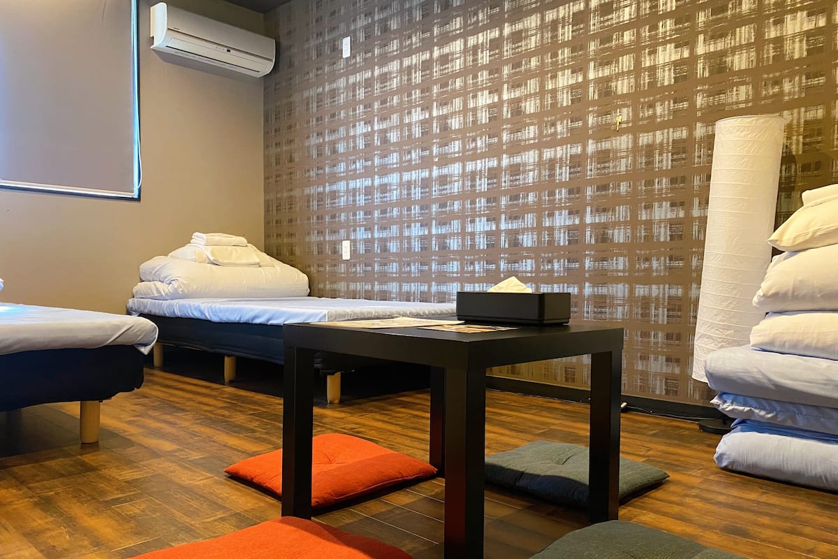 Quarto de hotel com duas camas, uma mesa e parede com padrão.