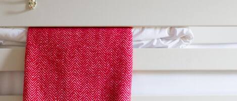 A white wall with a red and white patterned towel hanging on a white towel rack.