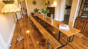 Una larga mesa de madera con bancos, una lámpara y un jarrón con flores.