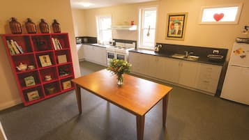 Een keuken met een houten tafel, een rode boekenkast en een raam met een hartversiering.